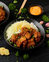 Japanese Fried crispy Chicken Karaage in black bowl with rice and cabbage