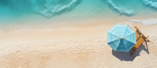 A tropical vacation setting with a sun lounger, umbrella, and beach gear on a sandy island, featuring copy space in a top-view image.