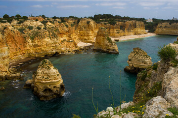 Top view of Marina Beach in Algarve Portugal with sand, blue Atlantic ocean and yellow rocks. Summertime. Selective focus. Travel concept