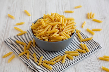 Raw Organic Dry Penne Pasta in a Bowl, side view.