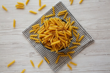 Raw Organic Dry Penne Pasta in a Bowl, top view.
