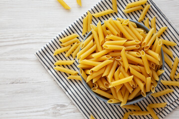 Raw Organic Dry Penne Pasta in a Bowl, top view. Copy space.