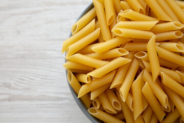 Raw Organic Dry Penne Pasta in a Bowl, top view. Overhead, flat lay, from above. Space for text.