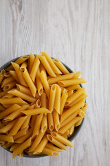 Raw Organic Dry Penne Pasta in a Bowl, top view. Overhead, flat lay, from above. Space for text.