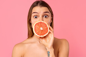 Woman with grapefruit on pink background representing wellness, beauty, and healthy lifestyle