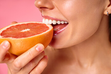 Woman savoring a grapefruit as a healthy snack, emphasizing wellness and nutrition