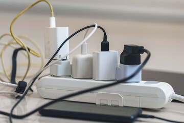 Electrical outlet with many chargers connected to it for a smartphone, laptop, microphone