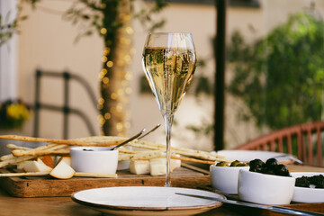 Elegant tall flute of chilled sparkling champagne with different snacks on an elegant formal dining table at outdoor cafe or restaurant in pedestrian street in Europe. Luxury served table at terrace. © Avalepsap