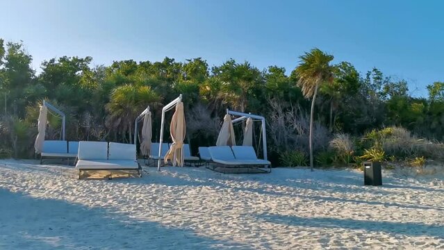 Palapa thatched roofs palms parasols sun loungers beach resort Mexico.