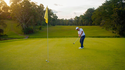 Blurred golfer playing golf in the evening golf course, on sun set evening time.