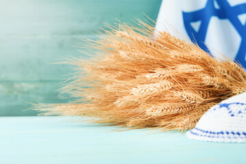 Shavuot jewish background. Ripe bouquet of wheat with blue ribbon against the background of Israeli...