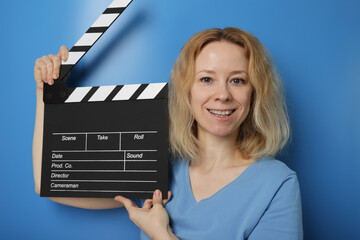 Woman claps clapperboard on blue background, movie tickets, sale discount, entertainment scene.