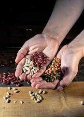hands holding a handful of legumes on a wooden table