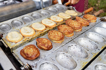 A street food vendor is cooking a traditional Korean snack called Bungeo-ppang, which is a fish-shaped pastry filled with red bean paste.