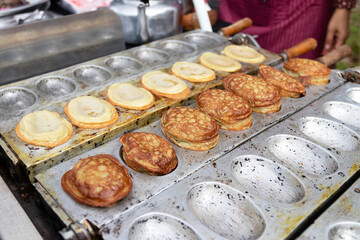 A street food vendor is cooking a traditional Korean snack called Bungeo-ppang, which is a fish-shaped pastry filled with red bean paste.