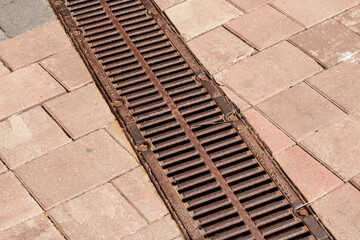 A drain on brick sidewalk with building materials and patterns