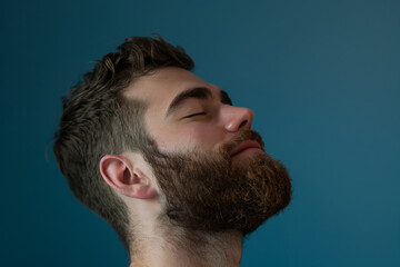 Obraz premium A close up of a man with beard and closed eyes looking to a side