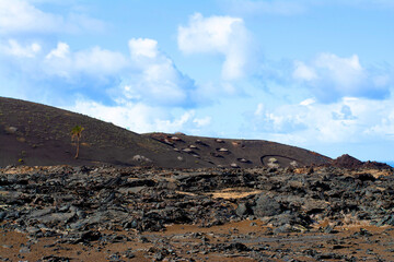 Black lava field and colorful mountains on hiking Termesana route (Ruta de Termesana) in Timanfaya national park, Lanzarote, Canary Islands , Spain