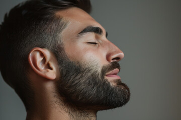 Obraz premium A close up of a man with beard and closed eyes looking to a side