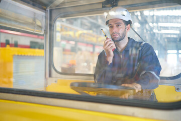 Engineer or worker talking on walkie talkie and driving a car in the factory