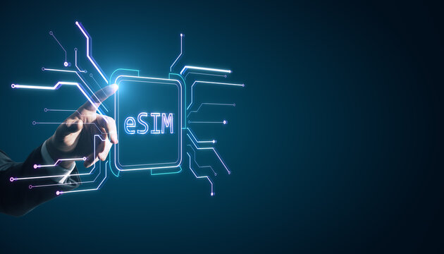 Close up of businessman hand pointing at creative glowing eSim hologram on blurry background with mock up place. Embedded sim and cellular mobile technology concept.