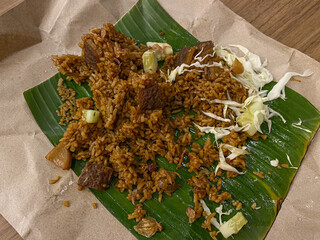 Indonesian fried rice or nasi goreng, with traditional wrap of brown paper and banana leaves