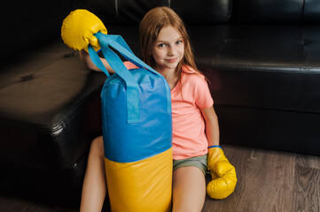 Happy strong beautiful teenage girl, Ukrainian athlete boxer child sitting indoors in a gym wearing...