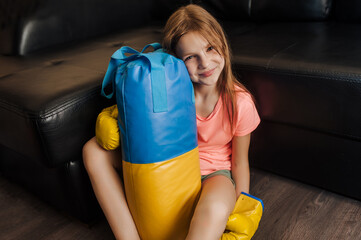 Happy strong beautiful teenage girl, Ukrainian athlete boxer child sitting indoors in a gym wearing...