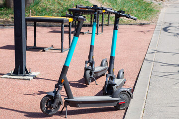 Parked electric scooters ready for rental in a park, with fitness equipment visible in the...
