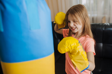 Happy strong beautiful teenage girl, Ukrainian athlete boxer child in the gym in boxing gloves hits...