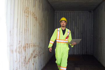 worker or engineer holding laptop computer and look around inside containers warehouse storage