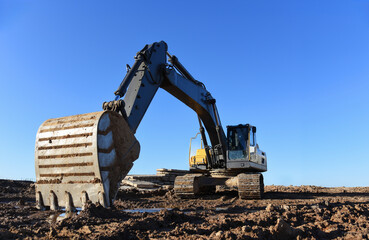 Excavator working at construction site on earthworks. Backhoe on road work digs ground. Paving out...