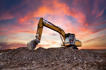 Excavator on earthworks at construction site on sunset background. Digging a foundation pit and a...