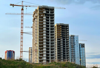 Fototapeta premium Construction site with buildings under construction. Tower cranes in action. Crane during formworks of house. Multi Storey Residential Buildings construction. Tower crane on Housing renovation.