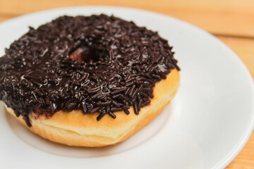 Close up a donut with chocolate sprinkles on a wooden table