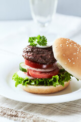 Tasty hamburger with tomatoes and onion. Bright wooden background.