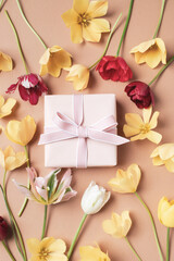 Beautiful aesthetic composition with gift box and flowers on neutral beige background. Greeting...