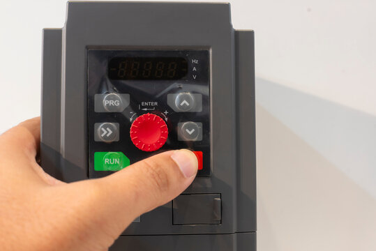 Close-up of a hand adjusting settings on an inverter variable speed drive. Perfect for concepts of technology, control, automation, and engineering.
