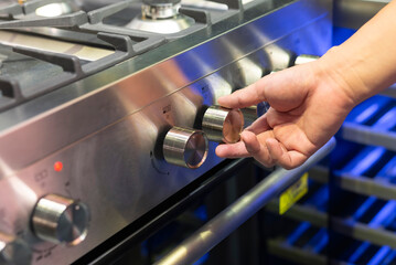 Hand adjusting temperature on modern stainless steel kitchen range