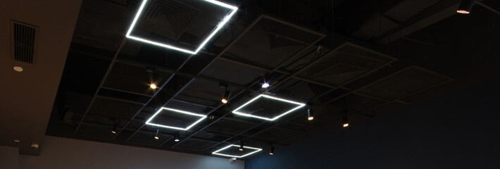 Black exposed ceiling with modern square led light industrial style metal frame grating and...