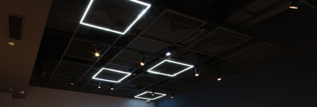 Black exposed ceiling with modern square led light industrial style metal frame grating and security camera - Powered by Adobe