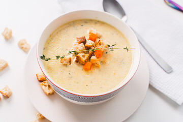 A healthy, dietary dish for lunch. Cream of vegetable soup with croutons and thyme. in a plate on a white table, view from above. selected focus.