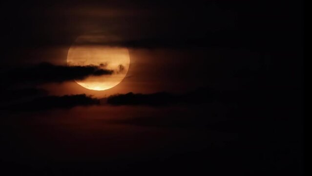 Full Moon behind black clouds. Clouds passing by the Moon create an spooky feeling like thriller and horror films. Real footage of the night sky