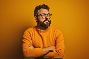 Obraz premium A man in a yellow sweater is sitting with his arms crossed