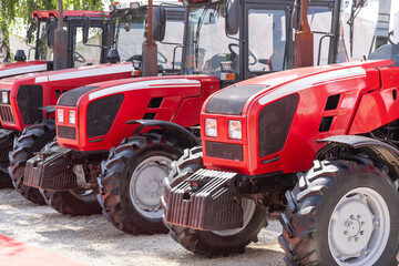 Row of red agricultural tractors for sale.