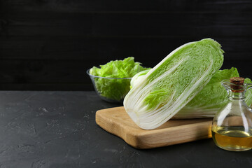 Fresh Chinese cabbages and oil on black textured table. Space for text
