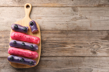 Different tasty glazed eclairs on wooden table, top view. Space for text