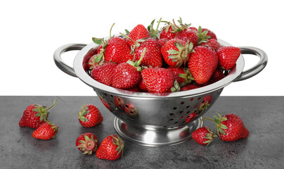Metal colander with fresh strawberries on grey table against white background