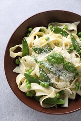 Delicious pasta with green peas and cheese on grey table, top view
