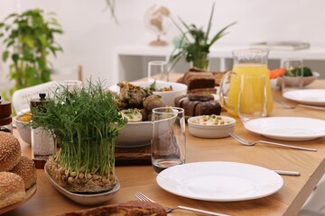 Healthy vegetarian food, jug of juice, cutlery, glasses and plates on wooden table indoors
